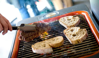 Steak and bread cooking on a Fusion charcoal BBQ at the Everdure by Heston Blumenthal BBQ experience.
