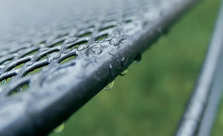 Raindrops on a metal mesh outdoor surface
