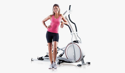 Woman stood next to cross trainer in workout clothes