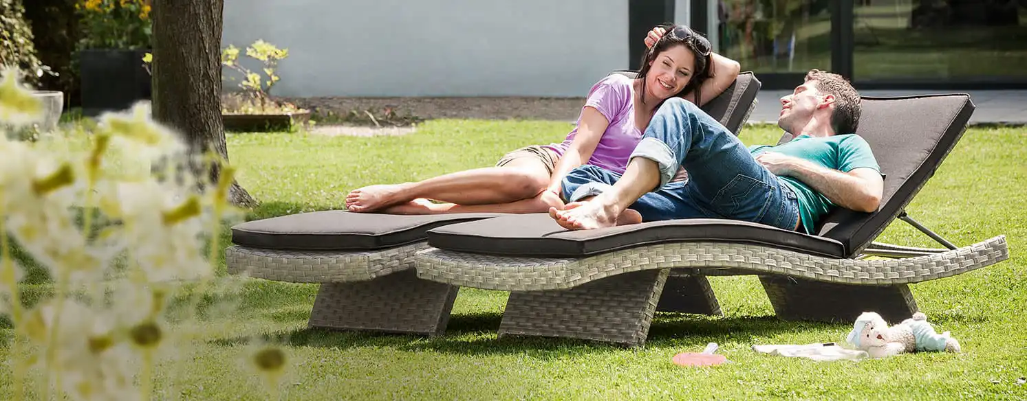 A man and a woman relaxing on sun loungers in the garden