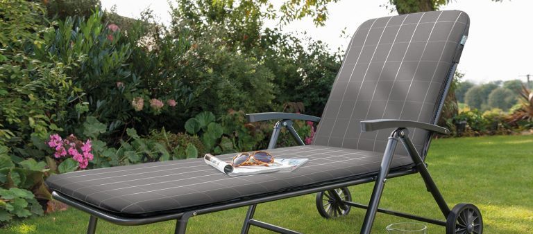 The Novero Lounger with Slate Check coloured cushions on a lawn in the garden.