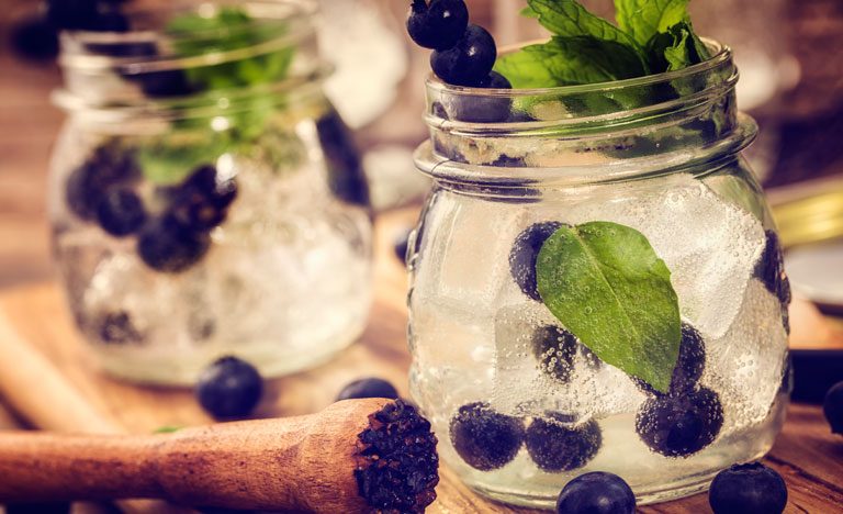 Blueberry gin mojitos with mint garnish in glass jam jars