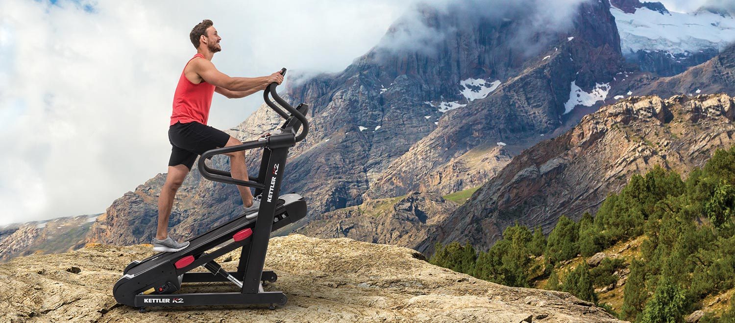 Young man exercising on the K2 High incline Treadmill in front of a mountain scenario