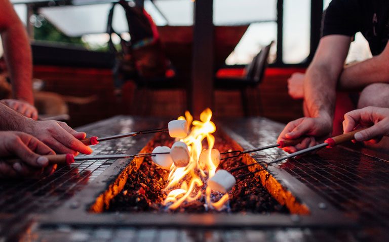 Close-up of marshmallows being roasted over a fire pit table.