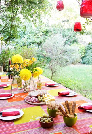 Table set for an outdoor meal in garden and decorated with flowers.