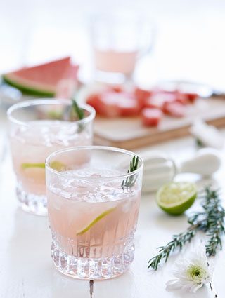 Pink gin with lime and rosemary garnish.