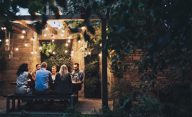 A group of people sitting around patio in the evening