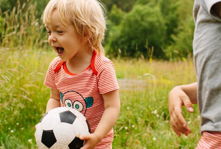 Two children playing football in a field.