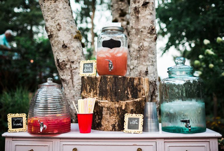 Large jars filled with drinks set on outdoor side table.