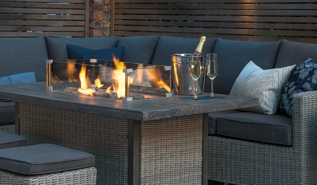 Close up of a lit Palma Fire Pit Table from the Kettler Palma garden furniture range, in a garden.