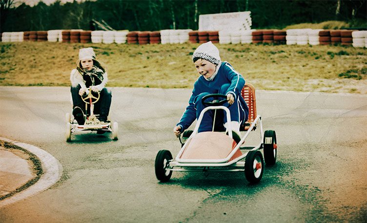 Two children racing go karts on track.