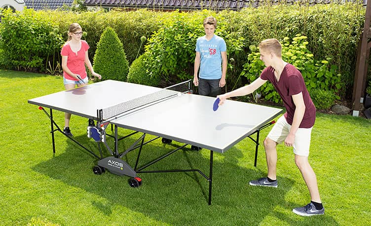 teenagers playing table tennis in garden