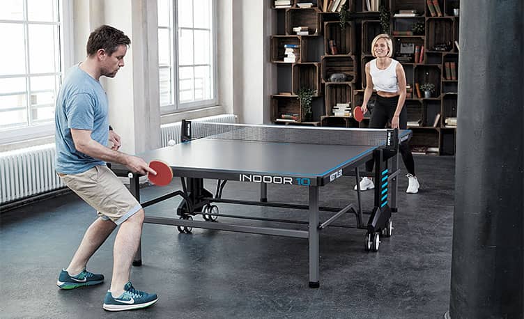 young couple playing table tennis indoors