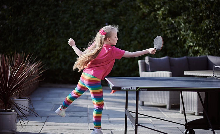 young girl playing table tennis outdoors