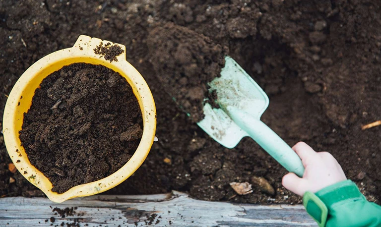 digging compost with trowel