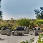 Palma luxe 2 seater sofa set in white wash wicker with grey cushions on a garden patio in the sunshine