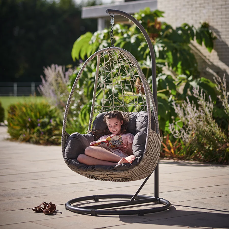 young girl reading a book sat in a Palma single cocoon hanging chair in the garden