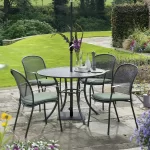 4 seater Caredo dining set in classic metal mesh with sage cushions on a garden patio in the sunshine