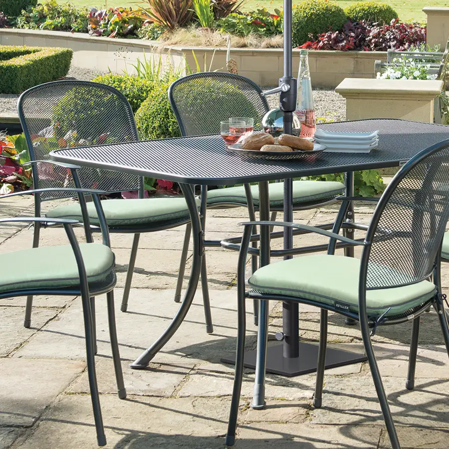 Mesh table with 6 cared chairs with sage cushions and parasol on garden patio
