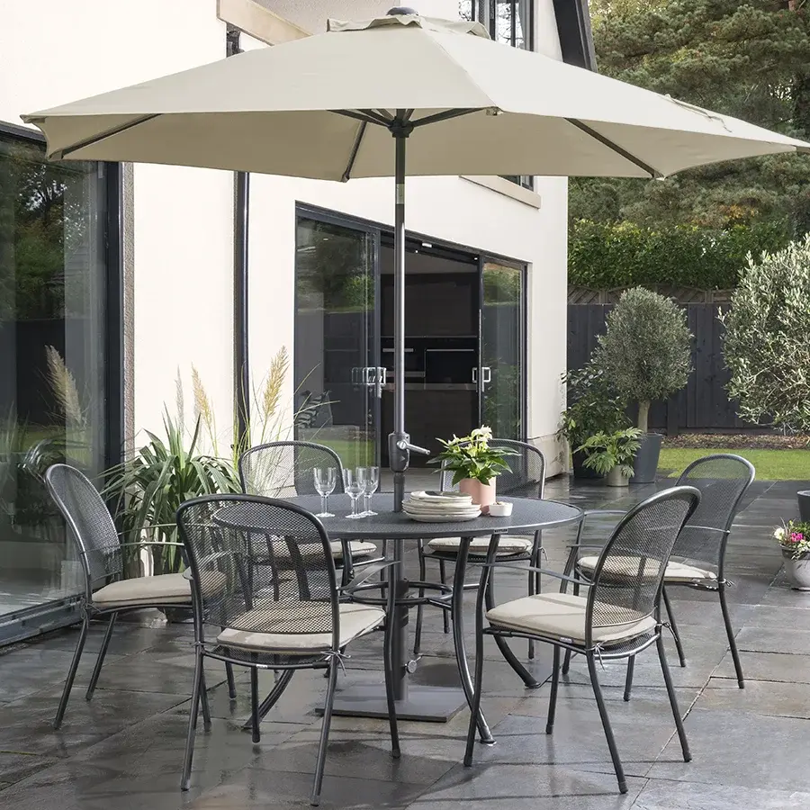 6 seater Caredo chair dining set in classic metal mesh with stone coloured cushions on a garden patio in the sunshine