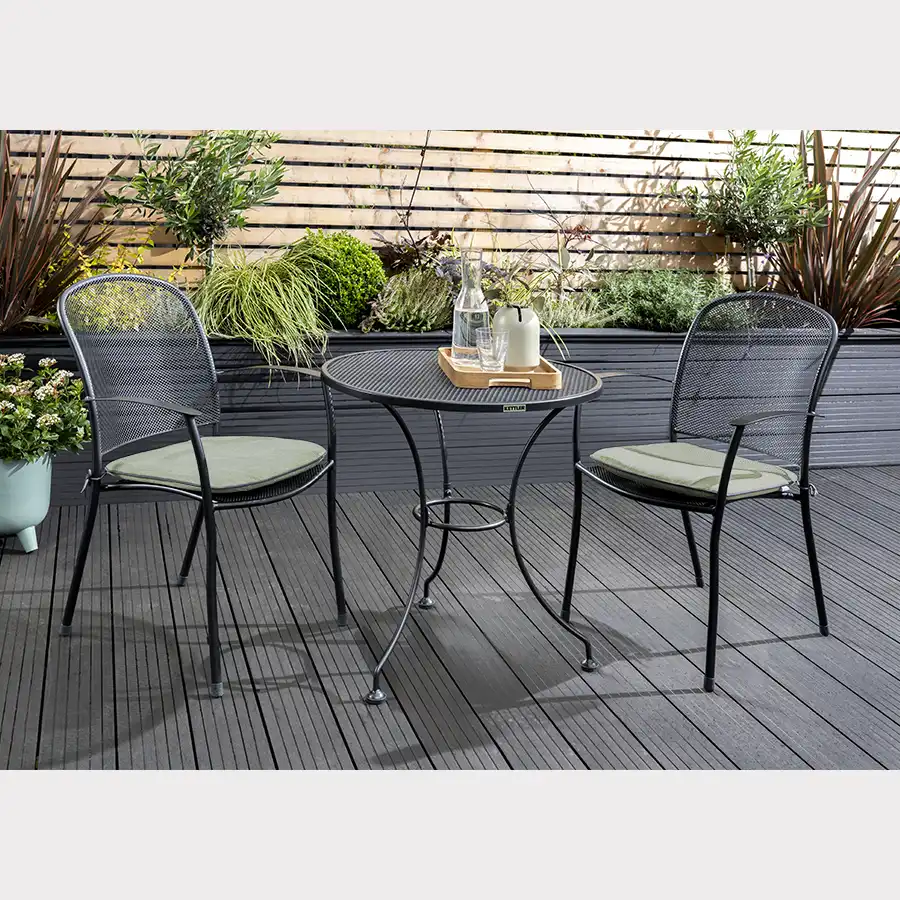 Caredo 2 seater bistro set in classic metal mesh with sage cushions on a garden decking in the sunshine