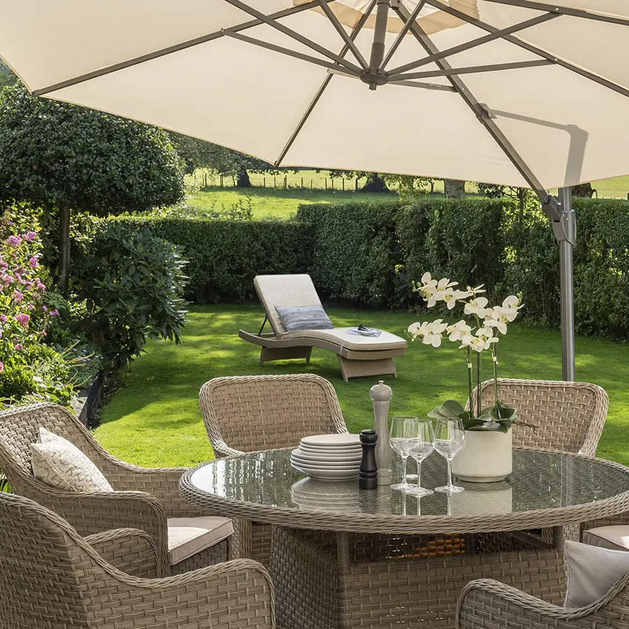 Charlbur 6 seater dining set with Charlbury universal wicker lounger in a garden on the grass
