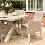 Cora wicker dining armchair made from fsc wood on a patio next to dining table