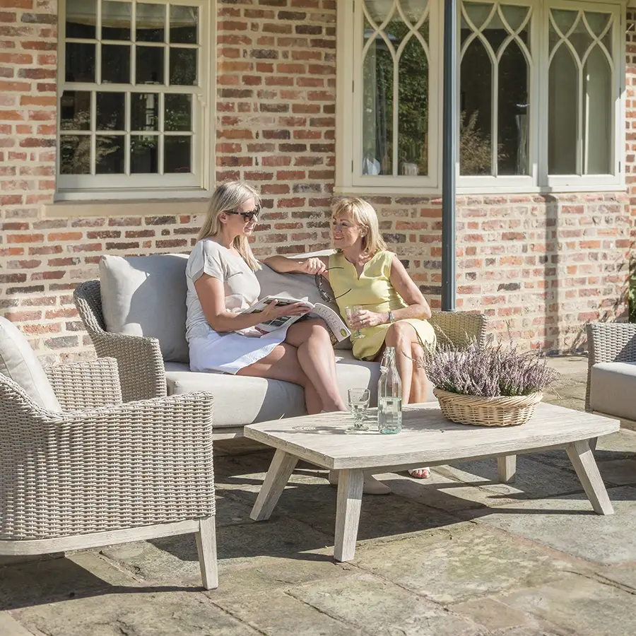 Cora wicker lounge set with 2 seater sofa, armchairs and coffee table with family relaxing in the sunshine