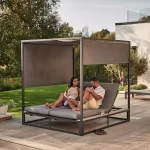 Elba day bed on a garden patio with couple relaxing