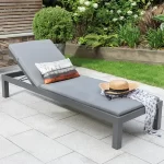Elba lounger in grey with back rasied on a garden patio with cushion and hat