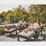 Couple relax on twor Elba relaxers with footstools on garden patio in the sunshine