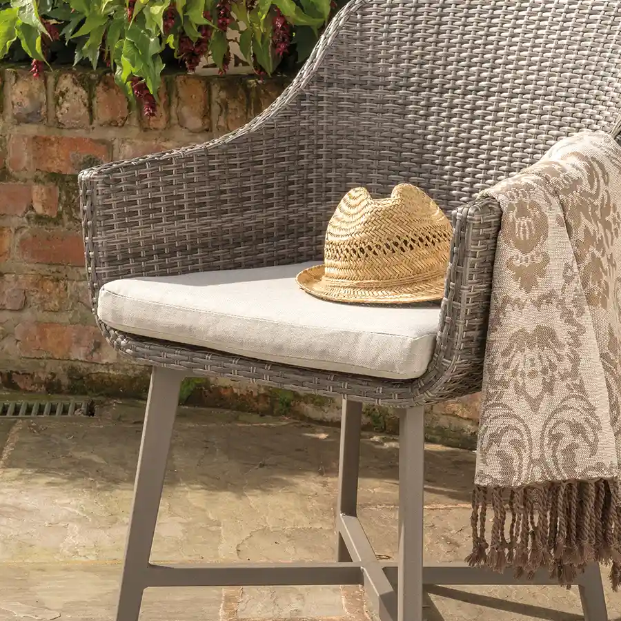 Detail of LaMode dining chair with hat left on the cushion in the sunshine
