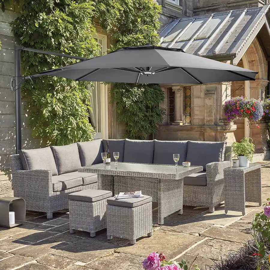 Palma wicker corner set with glass top table with parasol shade on a patio