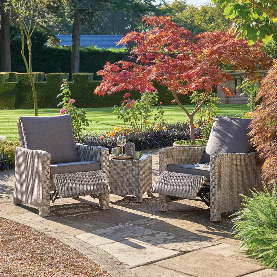 Palma Duo Relaxer set in white wash wicker with grey cushions with foot rest extended on garden terrace in the sunshine