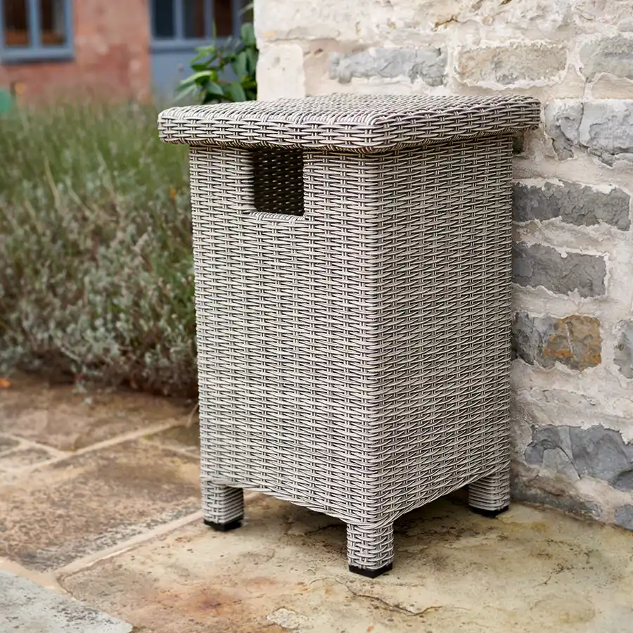 Palma Low gas bottle storage unit in white wash on a garden patio against a stone wall