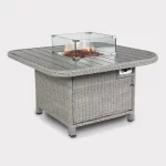 Palma Grande fire pit table in white wash wicker with fire lit on a plain white background