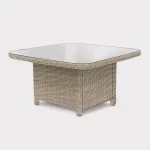 Palma Grande glass top table in oyster wicker on a plain white background