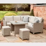 Palma mini corner set in oyster wicker with stone coloured cushions on a garden patio with brick wall behind