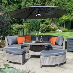 Palma casual dining round set in white wash in a garden setting with a parasol above