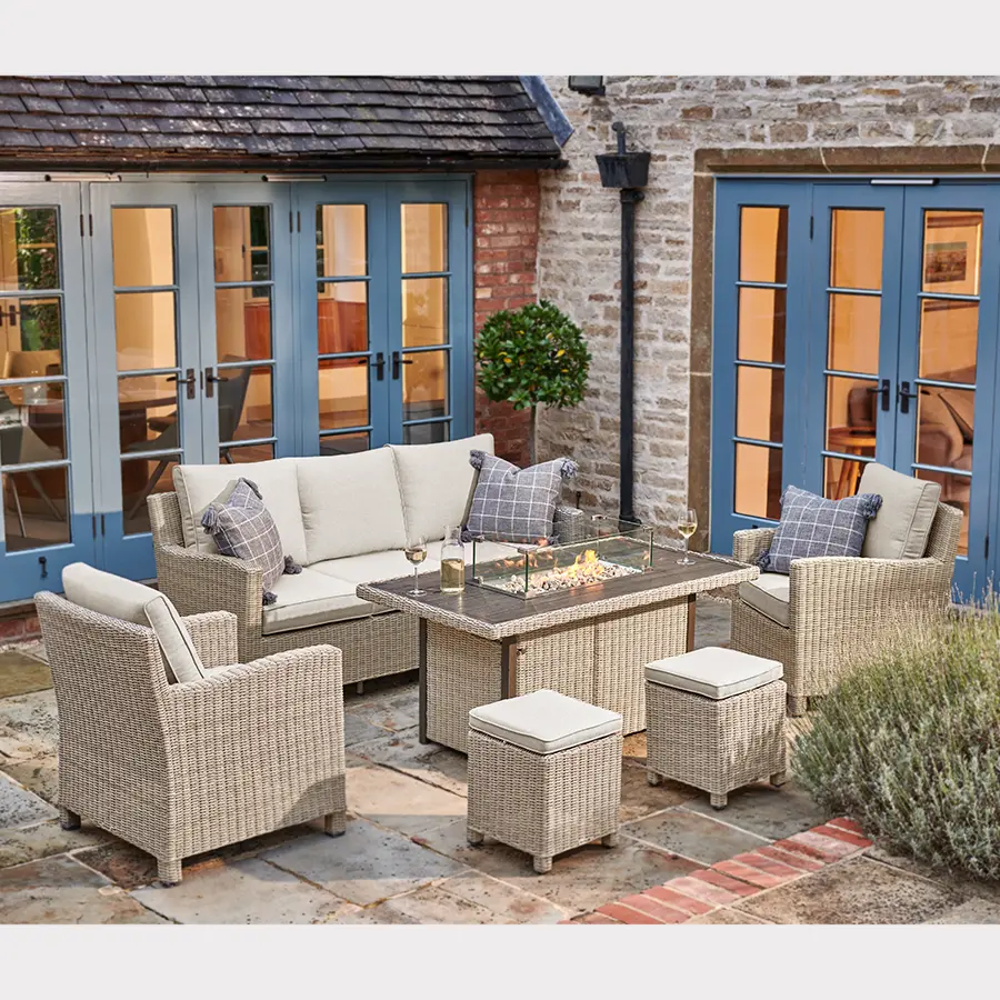 Palma Sofa Set in oyster wicker with stone cushions on a garden terrace with fire pit table burning in the evening