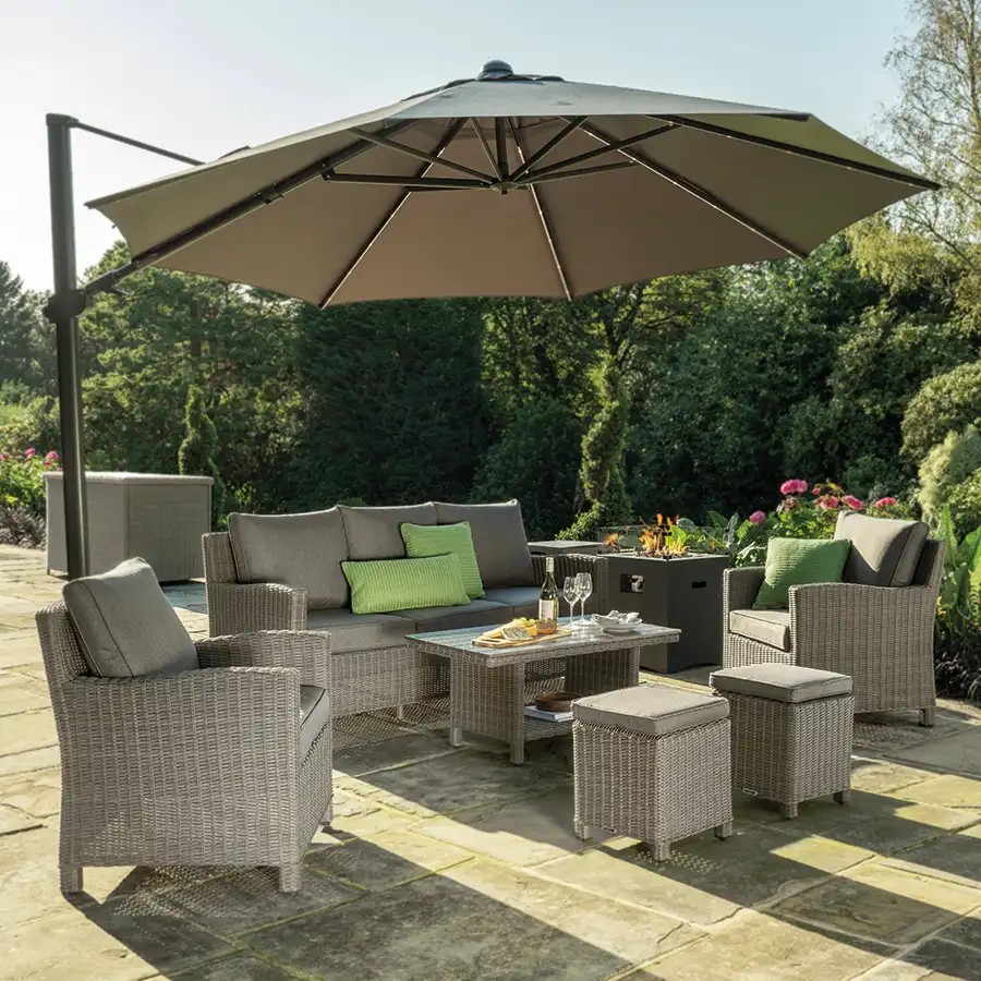 Palma Sofa Set in white wash wicker with grey cushions on a garden terrace underneath a large parasol