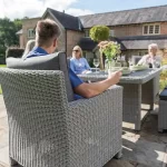 Family sat on a Palma Sofa Set in white wash wicker with grey cushions on a garden terrace