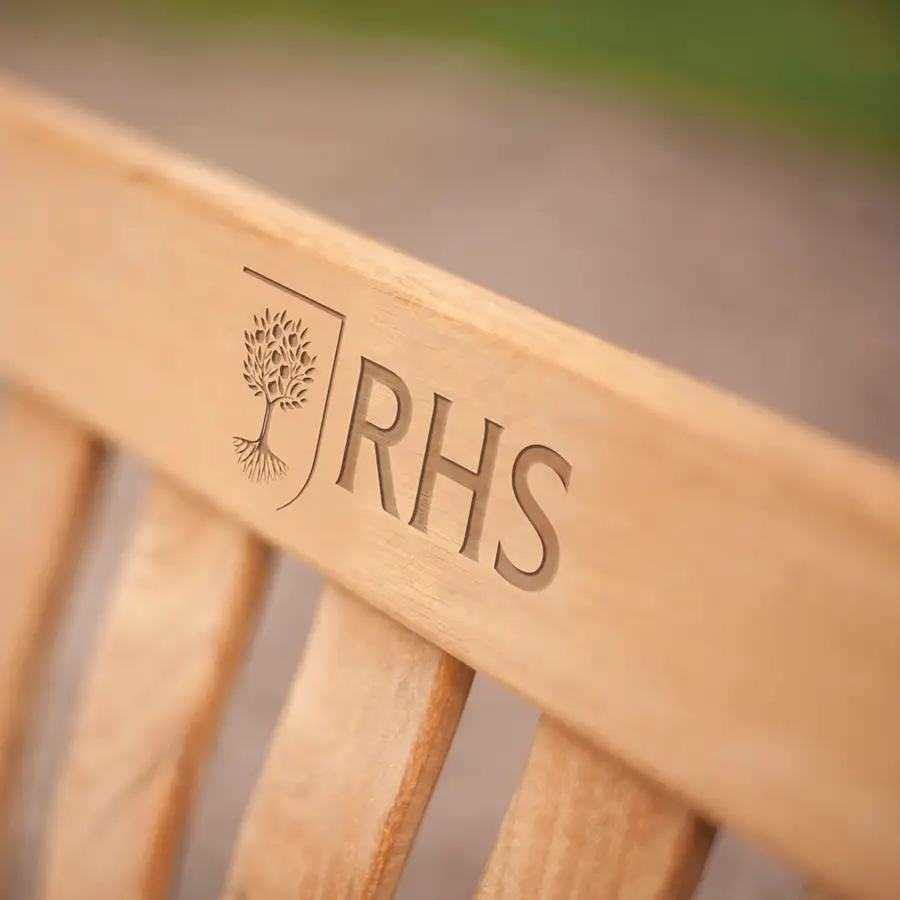 Detail of rhs logo carved into bench wooden slat