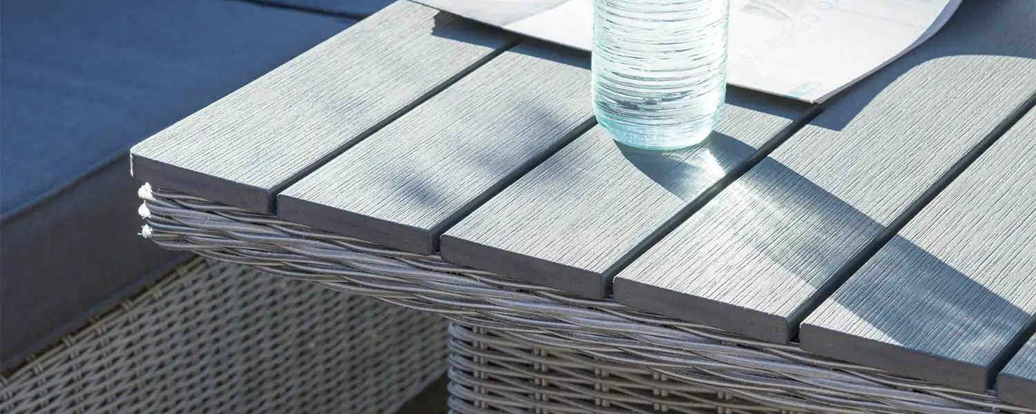 Close up of a wooden table top on wicker garden furniture.