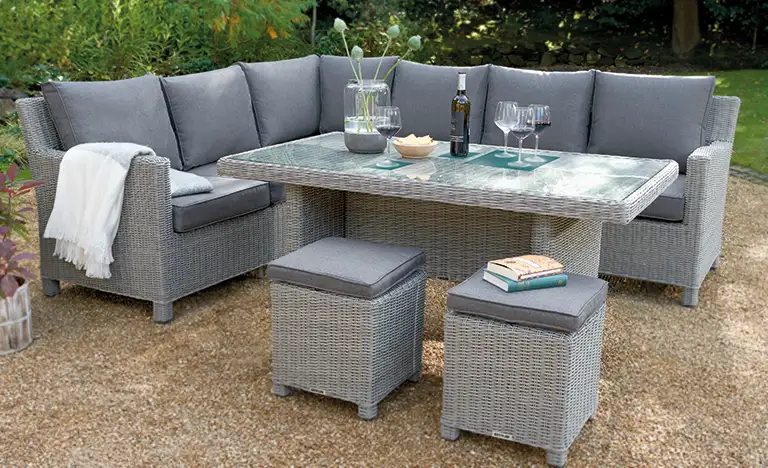 Palma Corner set in white wash wicker with glass top table on a gravel area in the garden
