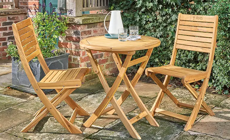 Wooden RHS Chelsea bistro set on a garden terrace in the sunshine