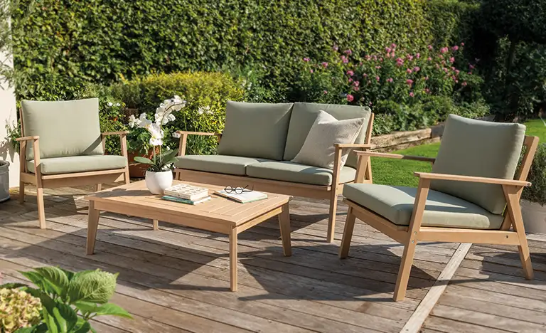 RHS Hampton wooden lounge set with green cushions on a garden decking in the sun