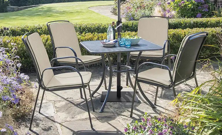 4 seater Savita dining set with stone cushions on a garden terrace in the sunshine