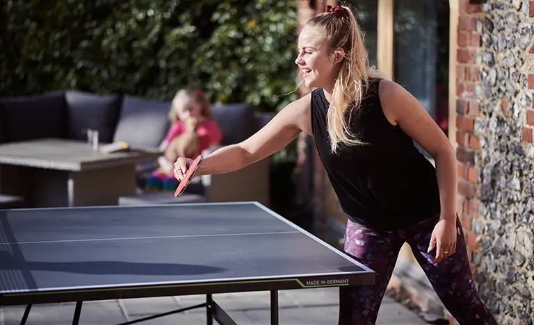 young woman playing table tennis in the garden