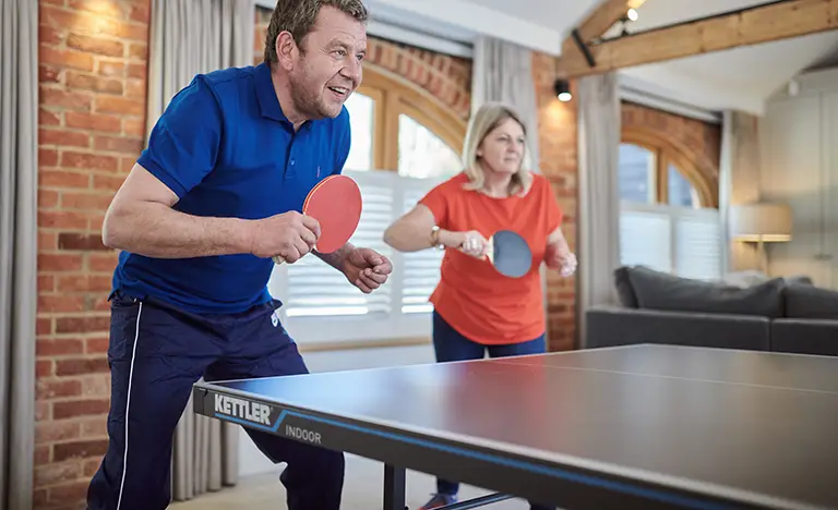 Man and woman playing table tennis indoors